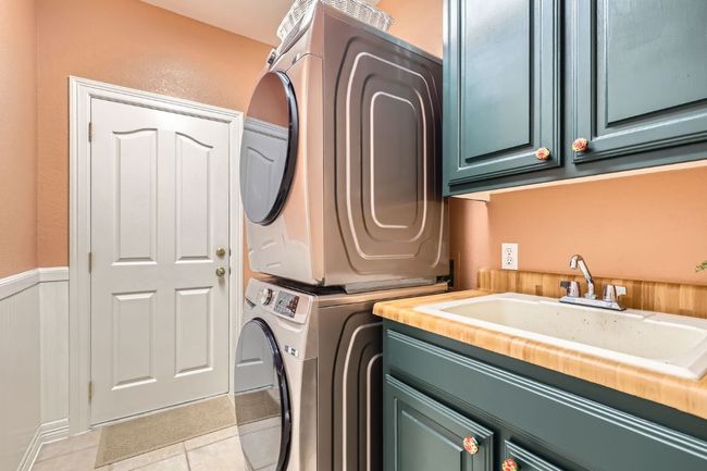 Laundry area with cabinet space, also accommodates side by side washer/dryer units, wainscoting, and light tile floor | Image 25