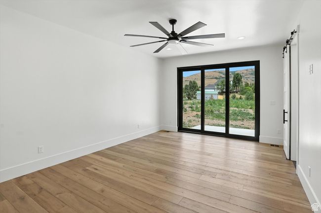 Spare room featuring a barn door, ceiling fan, light wood-style flooring, and recessed lighting | Image 27