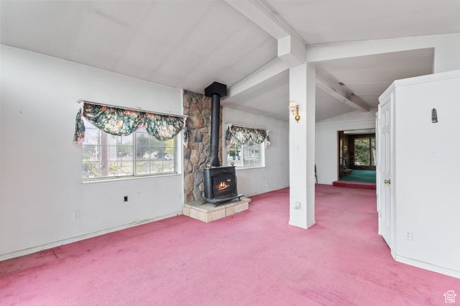 Unfurnished living room with carpet flooring, a wood stove, and healthy amount of natural light | Image 16