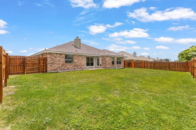 Rear view of house with a fenced backyard, brick siding, roof with shingles, and a chimney | Image 34