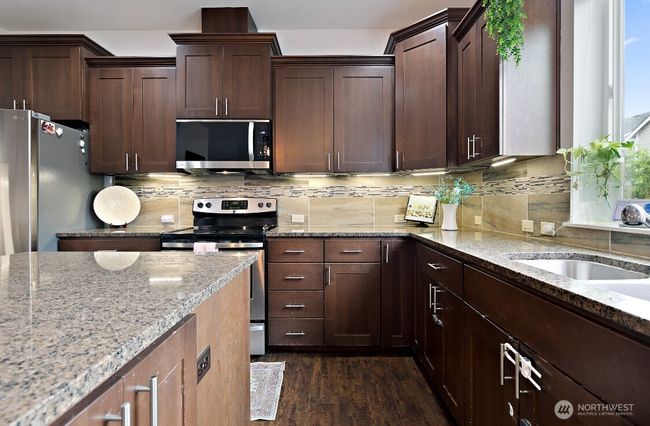 Beautifully updated kitchen featuring granite countertops, stainless steel appliances, and a large island with breakfast bar. | Image 5