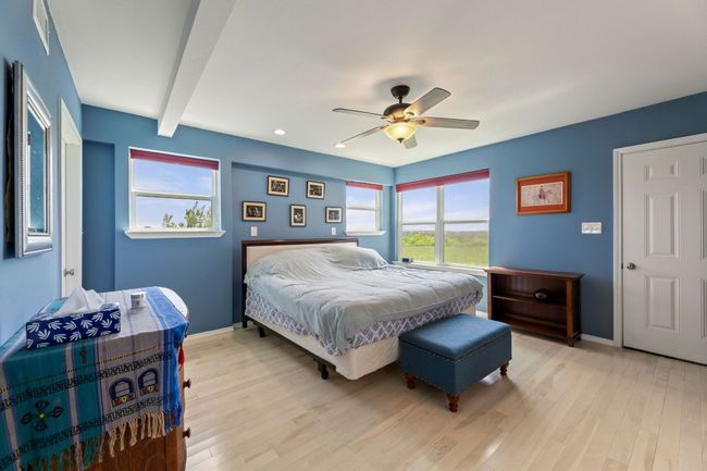 Bedroom featuring baseboards, multiple windows, light wood finished floors, and beamed ceiling | Image 16