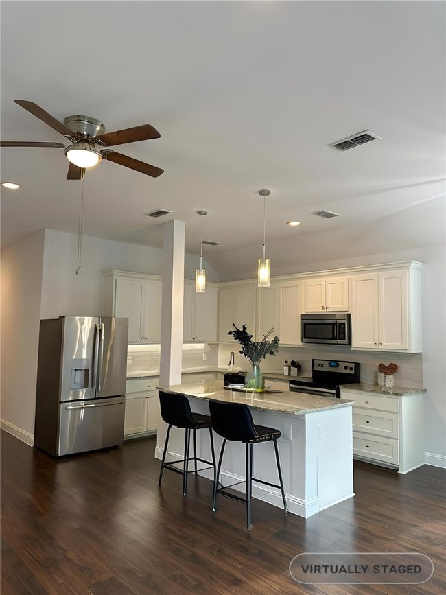Kitchen featuring appliances with stainless steel finishes, backsplash, a kitchen island, white cabinetry, and recessed lighting | Image 9