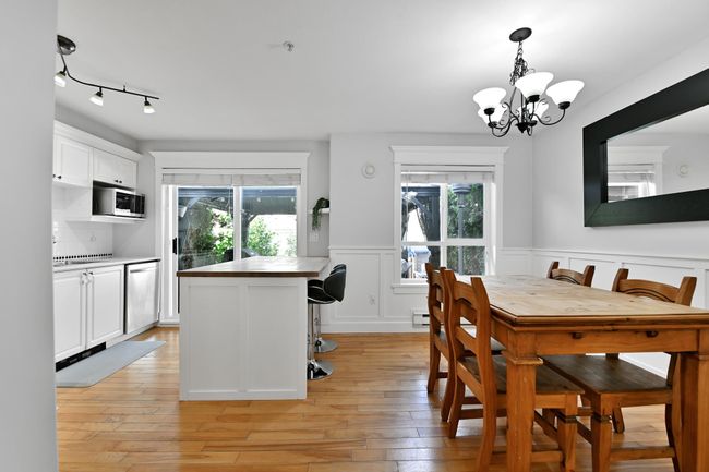 Dining space featuring a notable chandelier, light wood-type flooring, a wainscoted wall, and a healthy amount of sunlight | Image 16