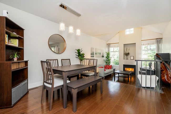 Dining space featuring baseboards, a lit fireplace, vaulted ceiling, dark wood-type flooring, and visible vents | Image 8