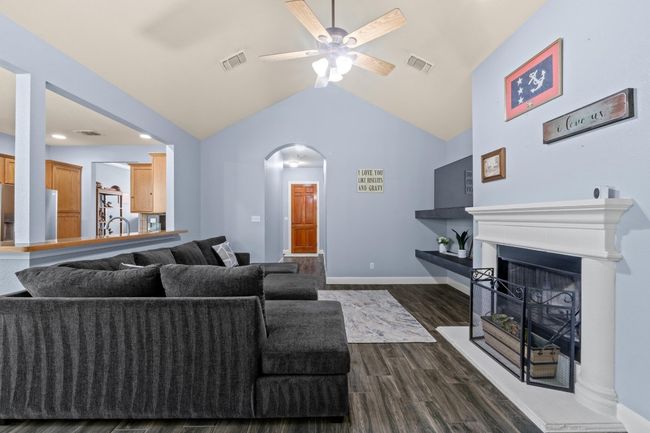 Living area with dark wood-type flooring, vaulted ceiling, a ceiling fan, and | Image 9
