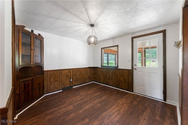 Unfurnished dining area featuring dark wood-type flooring, a wainscoted wall, and wood walls | Image 6