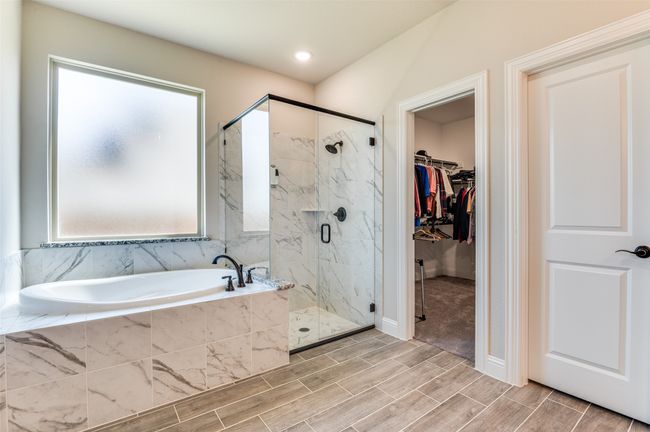 Bathroom featuring a bath, a marble finish shower, a spacious closet, and wood tiled floors | Image 26