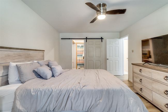 Bedroom with a barn door, light wood-style flooring, and ceiling fan | Image 13