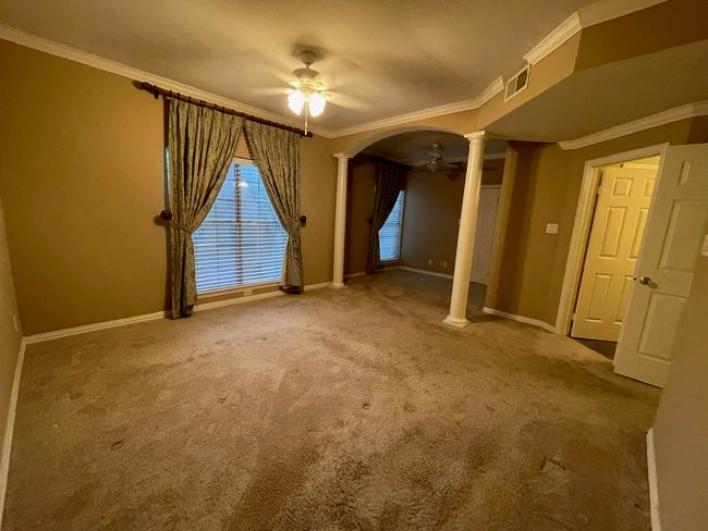 Carpeted empty room featuring ornate columns, ceiling fan, crown molding, and arched walkways | Image 11