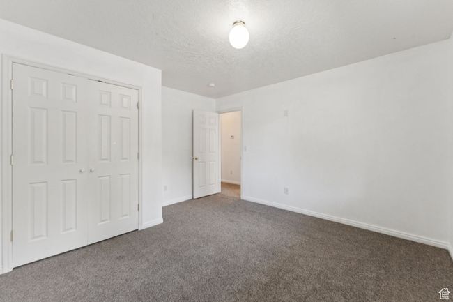 Unfurnished bedroom featuring carpet, a textured ceiling, and a closet | Image 12
