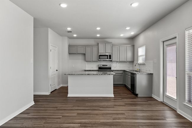 Kitchen with appliances with stainless steel finishes, gray cabinetry, backsplash, light stone counters, and recessed lighting | Image 11