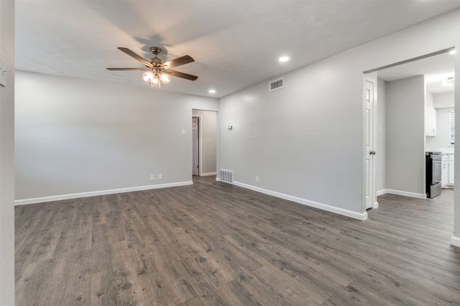 Empty room with ceiling fan, dark wood-type flooring, and recessed lighting | Image 20