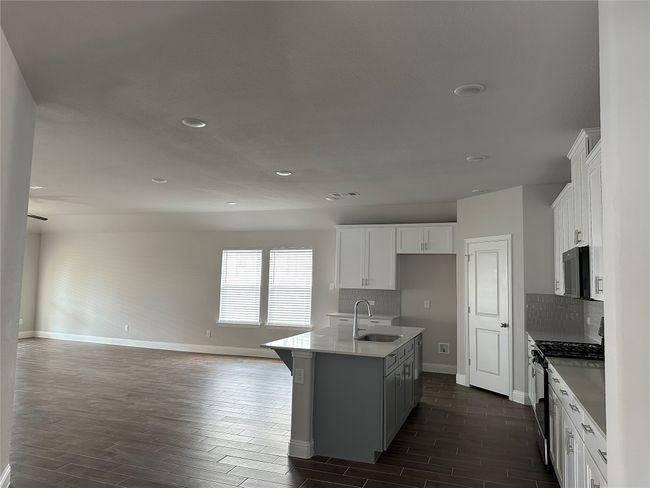 Kitchen with stainless steel appliances, open floor plan, wood finish floors, decorative backsplash, and recessed lighting | Image 6