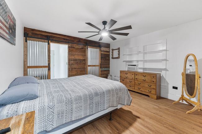 Bedroom with a ceiling fan, wood finished floors, and wooden walls | Image 14