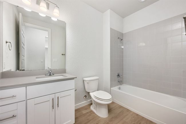 Bathroom featuring wood-like tile floors, vanity, tub/shower combination, and a textured wall | Image 9