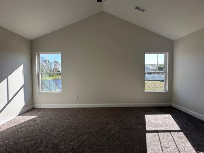 Spare room featuring dark colored carpet, visible vents, lofted ceiling, and plenty of natural light | Image 16