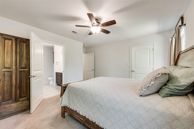 Bedroom featuring ceiling fan, ensuite bath, and visible vents | Image 22