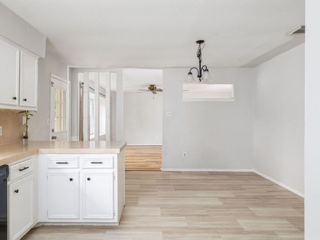 Kitchen featuring ceiling fan, light countertops, white cabinetry, light wood finished floors, and a peninsula | Image 10