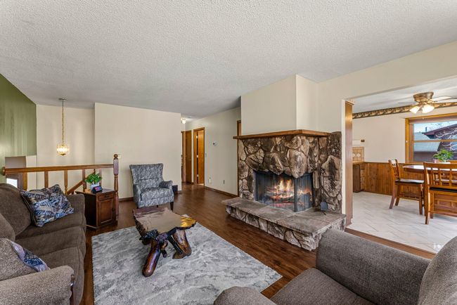The bright and airy upper-level living room serves as the heart of the home, boasting a charming wood-burning fireplace with a striking stone surround and wooden mantel—perfect for cozy evenings. | Image 4