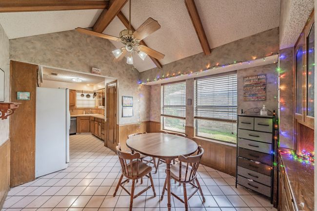 Dining space with a wainscoted wall, a ceiling fan, light tile patterned floors, wallpapered walls, and wooden walls | Image 9