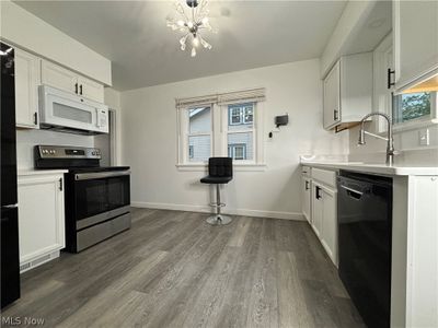 Kitchen featuring wood-type flooring, dishwasher, white cabinetry, and stainless steel electric stove | Image 3