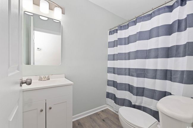 Full bath with toilet, wood finished floors, vanity, baseboards, and curtained shower | Image 13