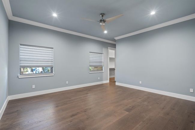 Primary bedroom with ceiling fan, baseboards, ornamental molding, and dark wood-style floors | Image 18