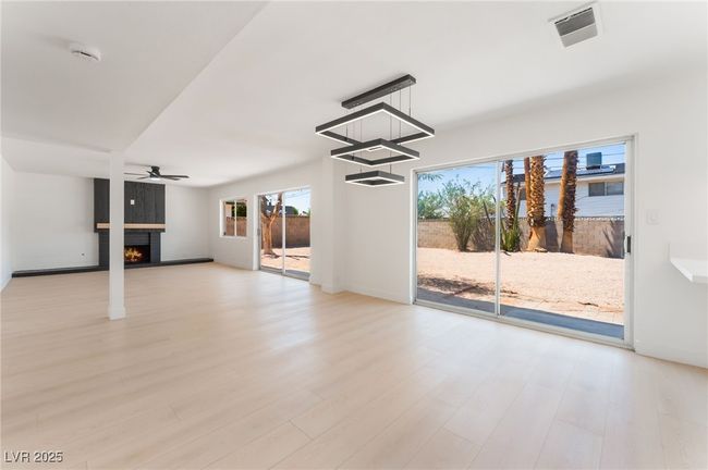 Unfurnished living room with a warm lit fireplace, wood finished floors, and ceiling fan | Image 14