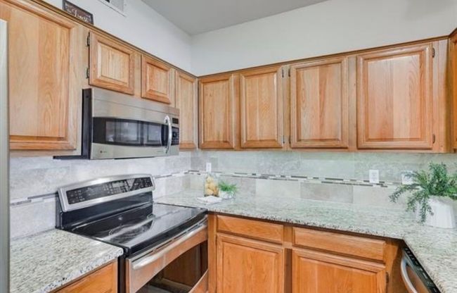 Kitchen featuring stainless steel appliances, tasteful backsplash, and light stone countertops | Image 6