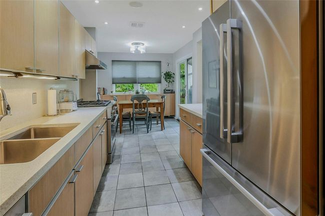 Kitchen with high end appliances, under cabinet range hood, a sink, light countertops, and recessed lighting | Image 18