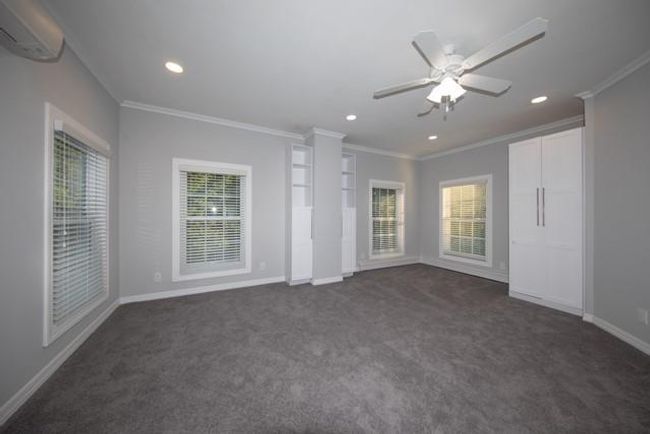 Unfurnished bedroom featuring dark carpet, a wall unit AC, crown molding, recessed lighting, and a ceiling fan | Image 7