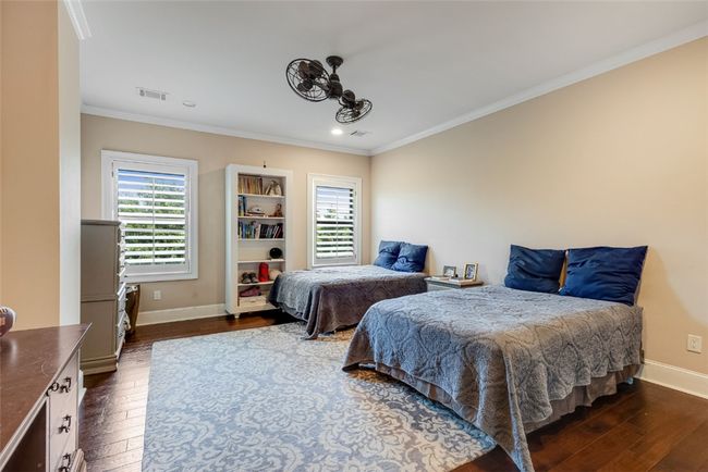 Bedroom with dark wood-type flooring, multiple windows, crown molding, baseboards, and recessed lighting | Image 13