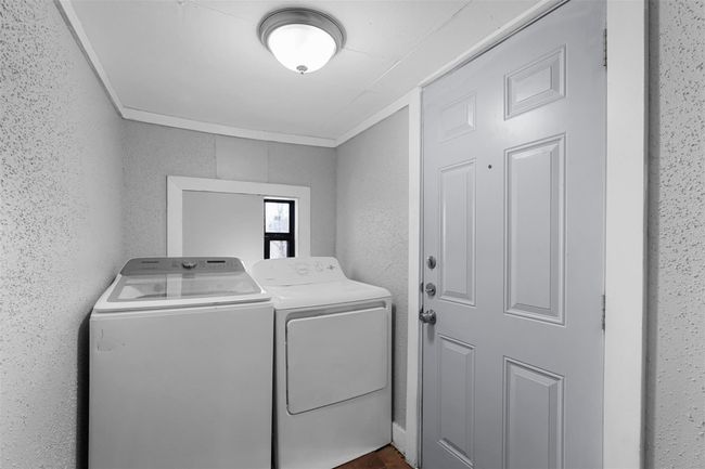 Laundry room with washing machine and dryer, a textured wall, and crown molding | Image 19