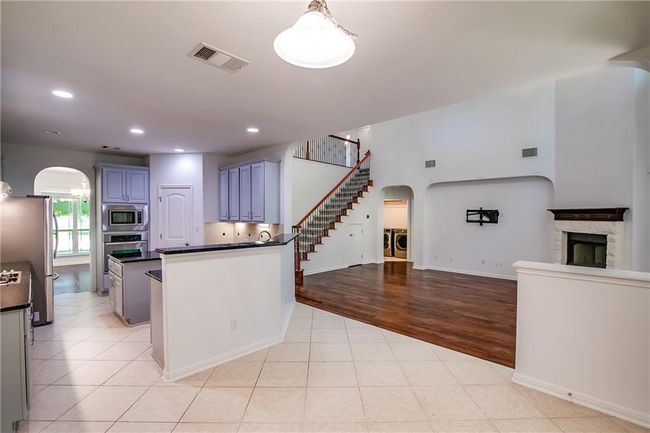 Kitchen with stainless steel appliances, independent washer and dryer, arched walkways, open floor plan, and dark countertops | Image 15