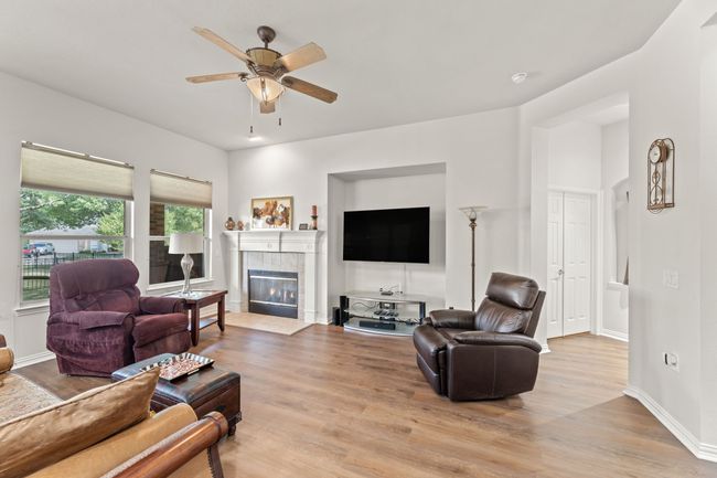 Living area featuring light wood-type flooring, a ceiling fan, a tile fireplace, and baseboards | Image 13