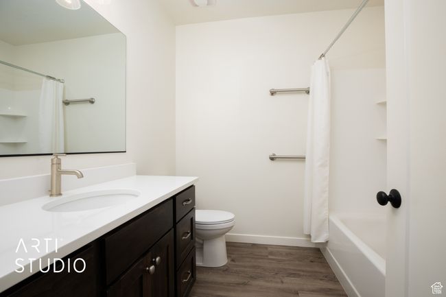 Full bathroom featuring shower / bathtub combination with curtain, vanity, toilet, and hardwood / wood-style floors | Image 37