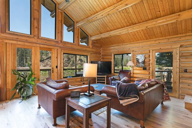 Living area with rustic walls, light wood-style floors, wooden ceiling with exposed beams, and high vaulted ceiling | Image 4