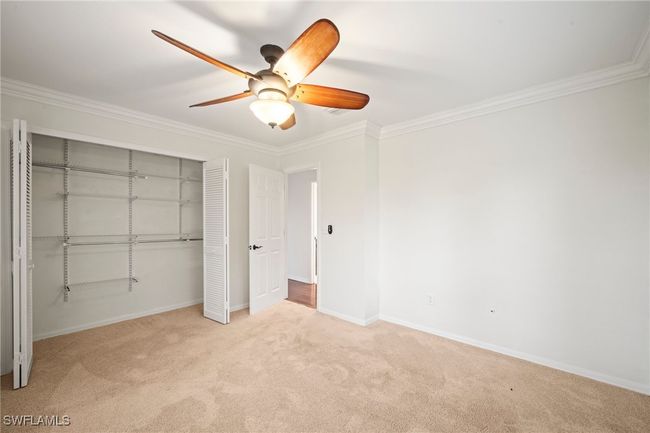 Unfurnished bedroom featuring carpet floors, ornamental molding, a closet, and a ceiling fan | Image 20