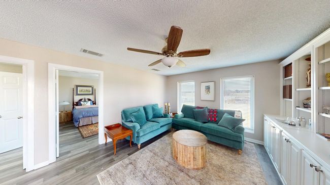 Guest Quarters Living room with a textured ceiling, light wood-type flooring, visible vents, and a ceiling fan | Image 24