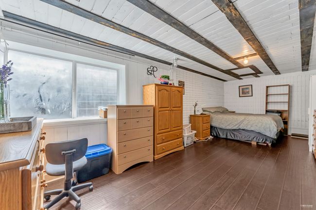 Bedroom with beamed ceiling, wooden walls, and dark wood finished floors | Image 31