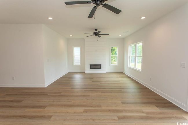 Unfurnished living room with healthy amount of natural light, recessed lighting, a ceiling fan, light wood-style floors, and baseboards | Image 9
