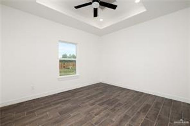 Unfurnished room featuring recessed lighting, dark wood-style floors, a tray ceiling, baseboards, and ceiling fan | Image 12