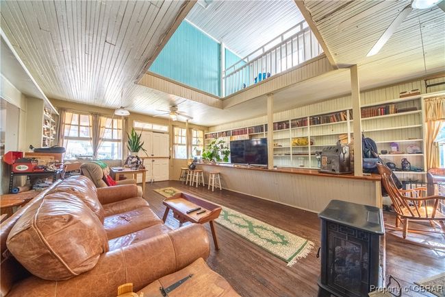 Living room featuring a wood stove, metal wall, wood finished floors, and a ceiling fan | Image 23
