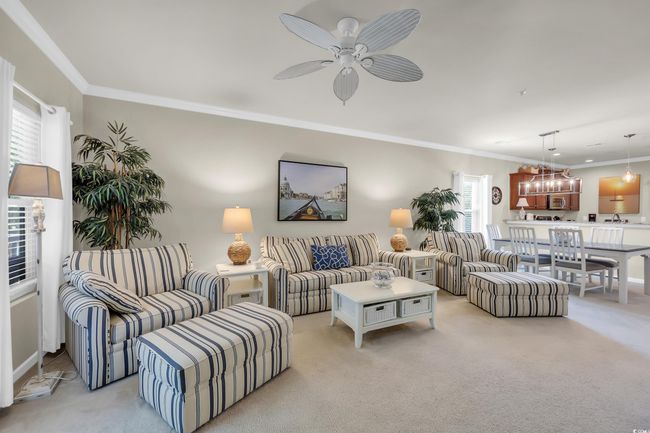 Living area featuring crown molding, light colored carpet, a chandelier, and a ceiling fan | Image 4