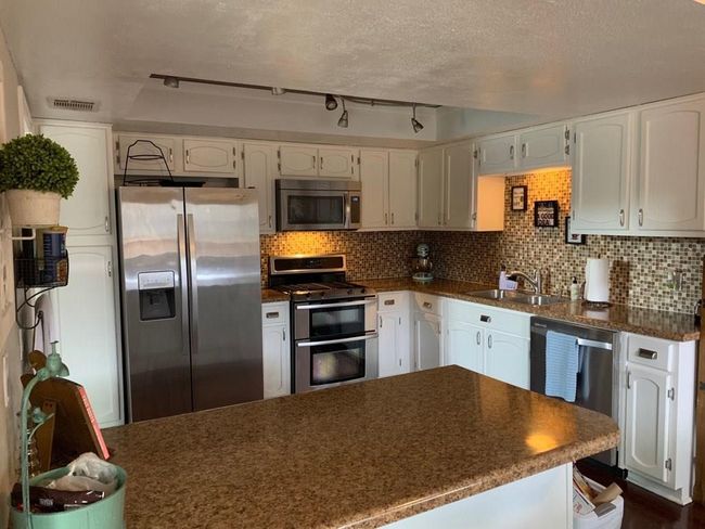 Kitchen with stainless steel appliances, a sink, and white cabinets | Image 7
