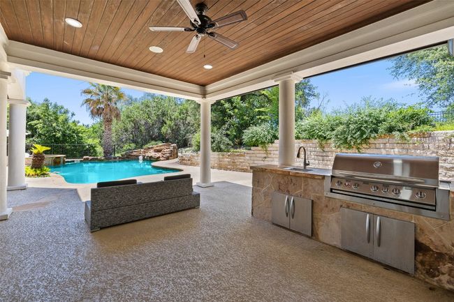 View of patio with grilling area, exterior kitchen, ceiling fan, an outdoor pool, and a sink | Image 32
