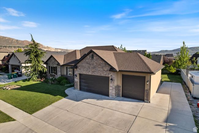 View of front of home with an attached garage, driveway, a mountain view, stone siding, and roof with shingles | Image 23