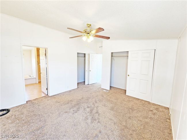 Unfurnished bedroom featuring carpet flooring, ceiling fan, two closets, and ensuite bath | Image 22