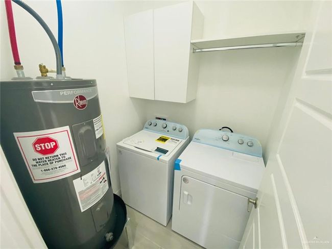 Laundry room featuring water heater, cabinet space, washer and clothes dryer, and light tile patterned floors | Image 13